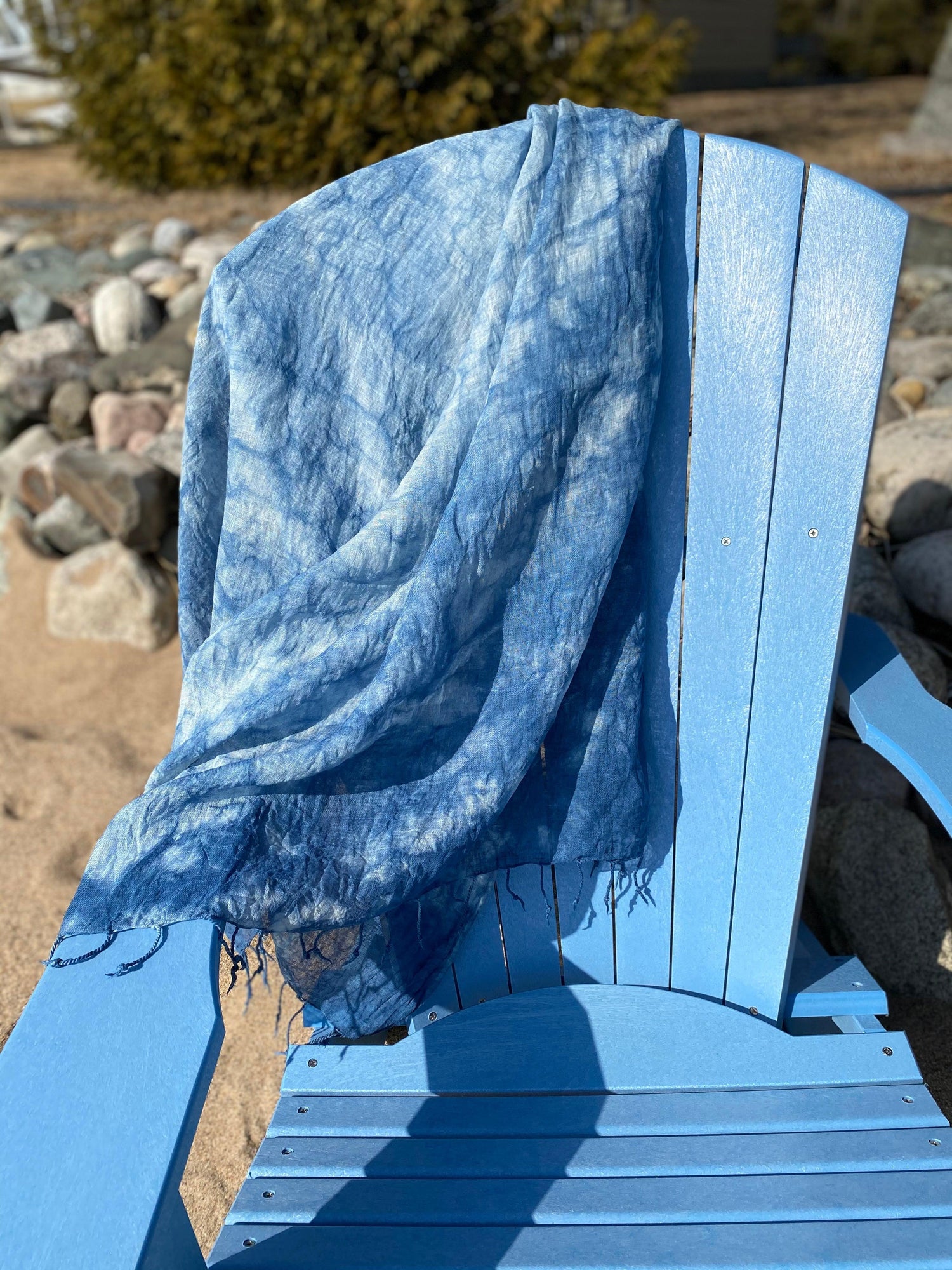 Indigo handwoven linen shawl resting on a blue adirondak chair